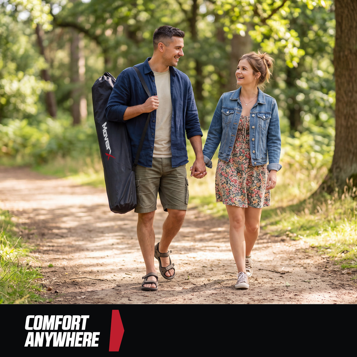 Couple walking in a forest, man carrying a black MoverX folding camping bed in a carry bag.